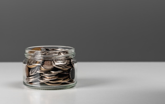 Coins in glass jar currency money on dark gray background for business and finance concept