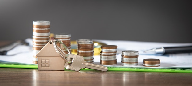 Coins house model and keys on the table