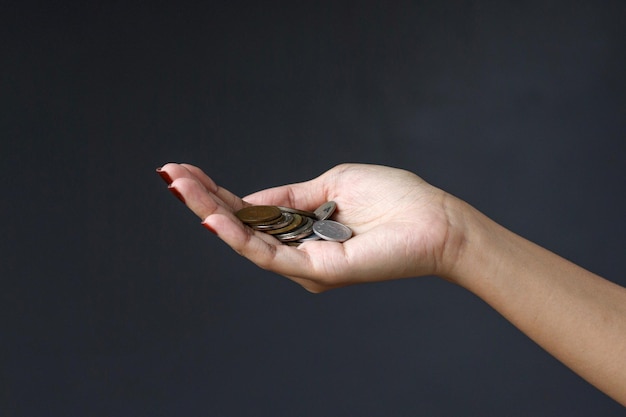 Coins in palm of woman hand isolated on dark gray background.