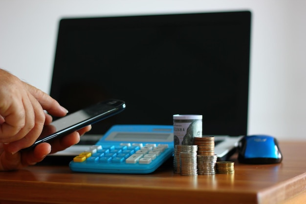 Coins stack on wood table while worker us ing mobile phone searching money information money concept