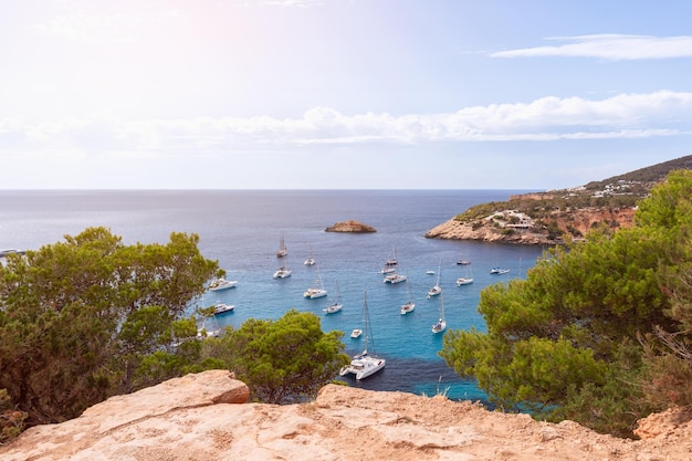 Cola d'Hort bay with blue water and surrounded by yellow sandy cliffs and green pine trees Ibiza