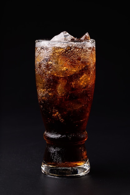 Cola in glass with clear ice cubes isolated on black background