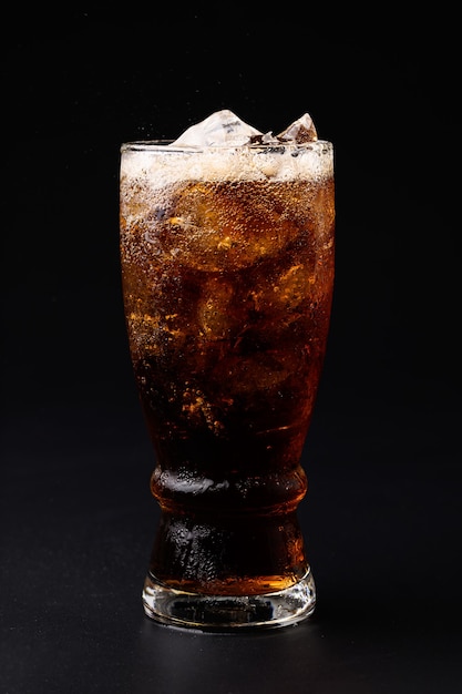 Cola in glass with clear ice cubes isolated on black background