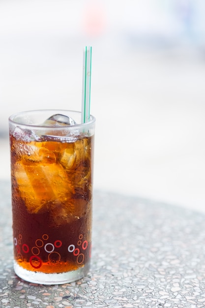 Cola in glass with ice on table background