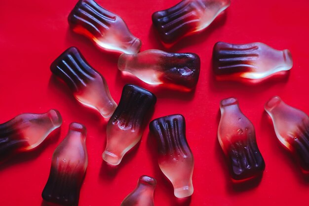 Cola gummy jelly candies in bottle shape, sweet backdrop