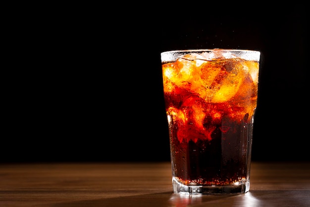 Cola soda glass with ice cubes on wooden table