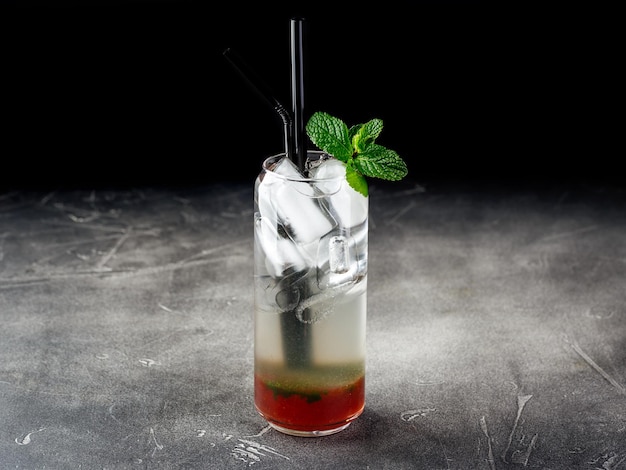 Cold alcoholic or nonalcoholic cocktail with ice on dark background