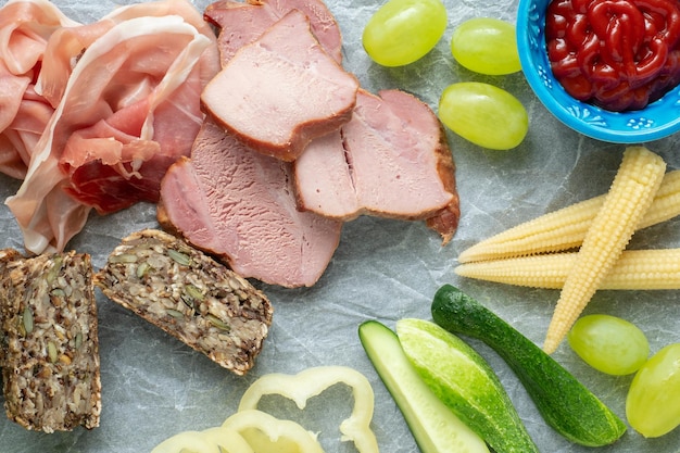 Cold appetizer Cold cuts Different snacks on a white crumpled paper bacon fruits grapes