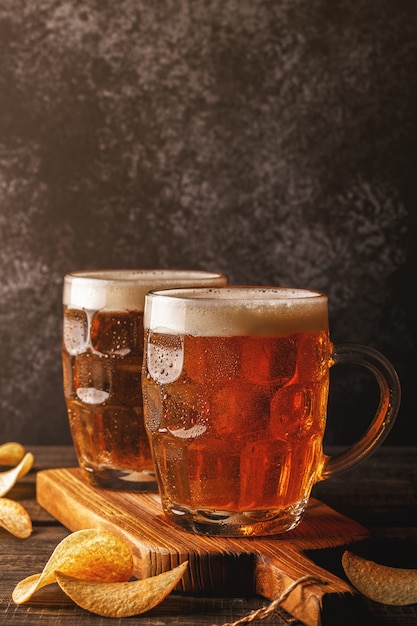 Cold beer in glass pints on a wooden board