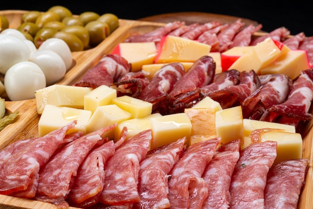 Cold cuts board with salami and different types of cheese and olives.