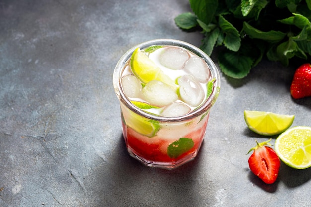 Cold detox water with lime strawberry mint in the glass with ice cubes on gray background copy space