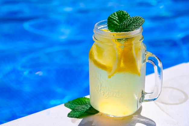 Cold drink lemonade on the background of the pool