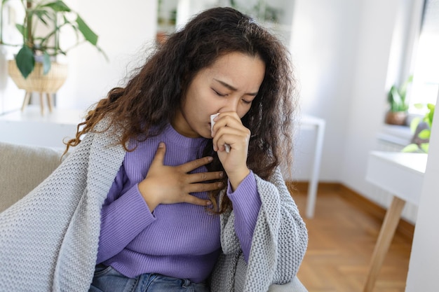 Cold flu cough Sick woman coughing sitting on sofa at home Asian woman being sick having flu lying on sofa Cold flu coronavirus covid19