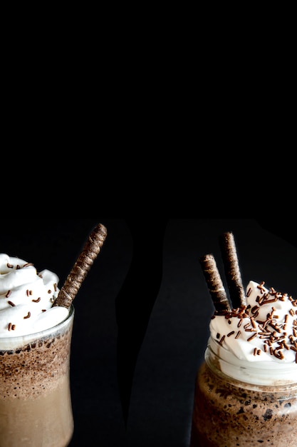 Cold frappe coffee with whipped cream. Black background with iced frappuccino.