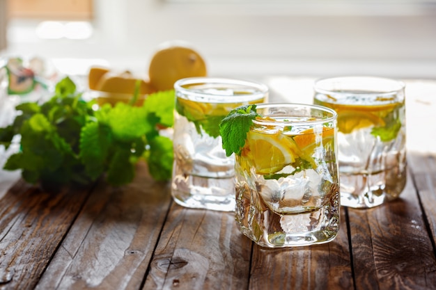 Cold fresh lemonade with lemon and mint on wooden background