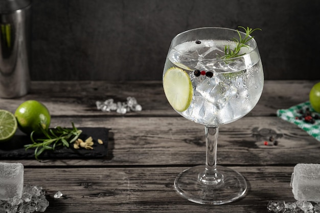 Cold glass of gin tonic with ice on dark rustic background