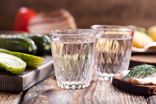 Cold glasses of vodka with traditional russian snack on wooden table