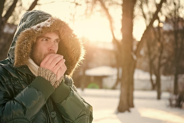 Photo cold and loneliness male in down coat with fur hood feel warm and comfortable favorite season guy green puffer coat man enjoy winter landscape nature is beautiful place for thoughts