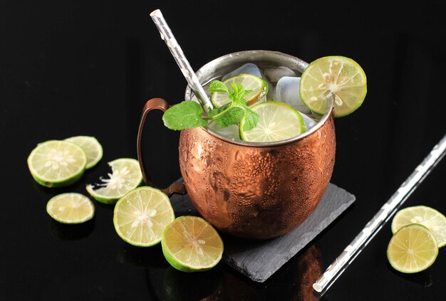 Photo cold moscow mule coctail on copper mug with ginger beer lime and vodka garnish with mint leaf