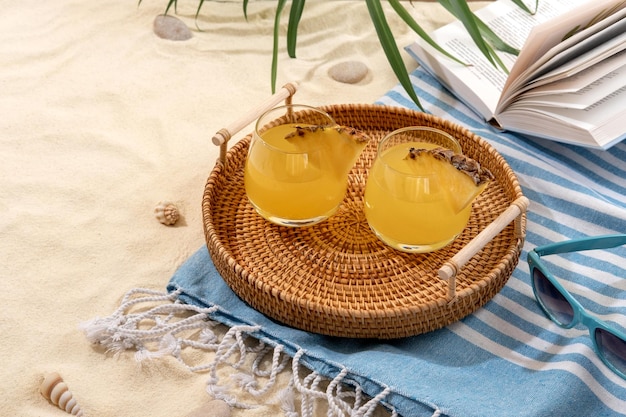 Cold pineapple cocktails on a wicker tray on beach with white sand Summer sea vacation and travel concept Exotic summer drinks