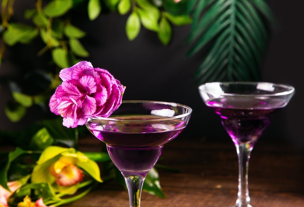 Photo cold purple violet exotic cocktail in glass with decorated flowers and petals tropical vibes