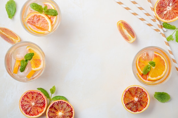 Photo cold refreshing drink with blood orange slices in a glass on a white concrete table