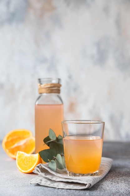 Cold and refreshing fresh orange juice in glass and bottle with fresh orange grey background