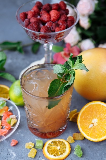 Cold refreshing pineapple cocktail with lime and mint for a hot summer day on a gray background decorated with candied fruit, mint and pineapple cubes.