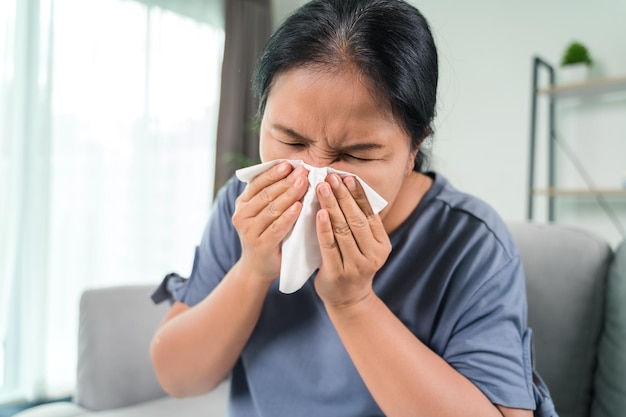 Cold sick woman got nose allergy cough or sneeze with tissue paper sitting on the sofa Healthcare