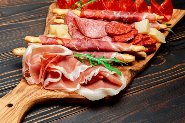 Cold smoked meat plate with pork chops, prosciutto, salami and bread sticks