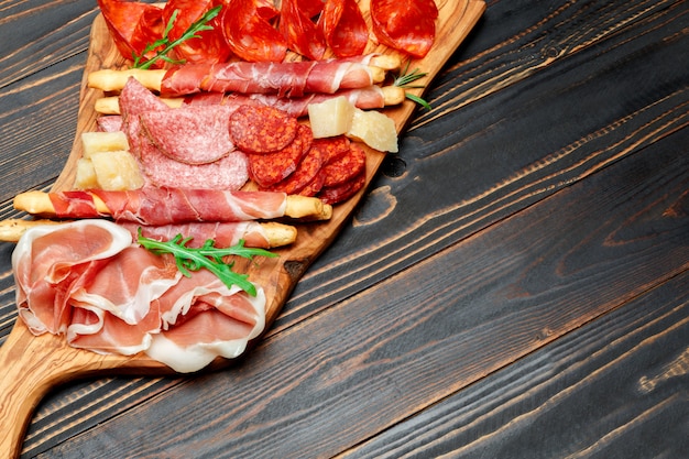 Cold smoked meat plate with pork chops, prosciutto, salami and bread sticks