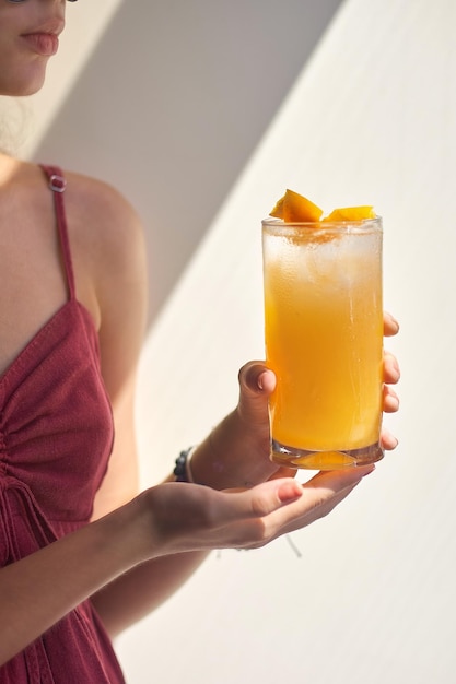 Cold summer cocktail in the female's hand closeup woman's hand holds a misted glass of a refreshing cocktail