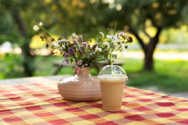 Cold summer drink and Bouquet of summer flowers in vase in garden