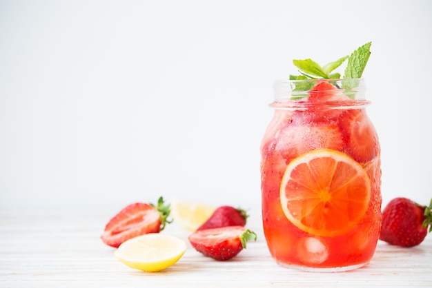 Cold summer strawberry lemonade in a jar on a white background, selective focus, copy space