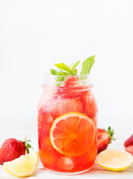 Cold summer strawberry lemonade in a jar on a white background, selective focus, copy space