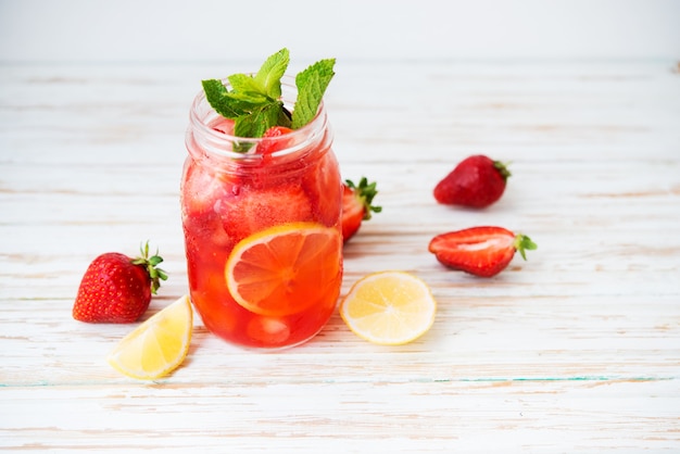 Photo cold summer strawberry lemonade in a jar on a white background, selective focus, copy space