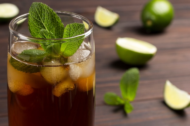 Cold summer tea with ice and mint. On table lime and mint leaves.