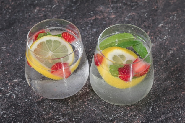 Cold water with berries and lemon in two glasses