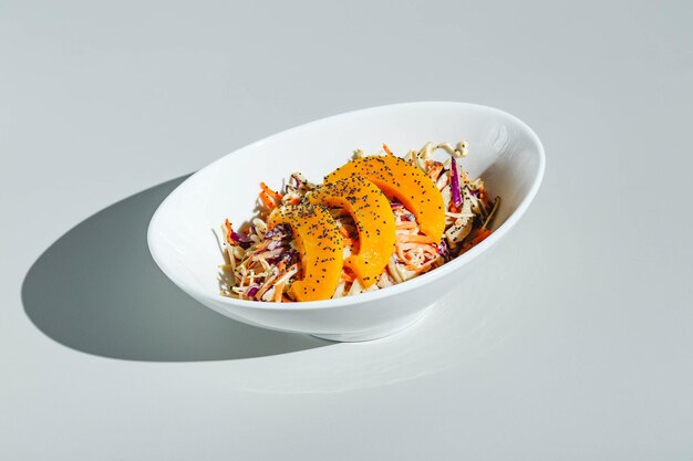 Cole slow salad with mango and poppy seeds on light background hard light deep shadow