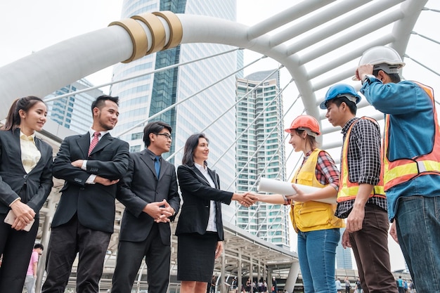 Collaboration of multiethnic group of engineers and businessperson handshake with contract agreement of big project in the city