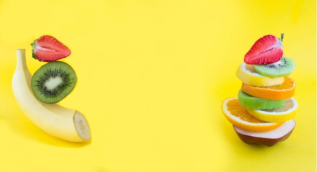 Collage Pyramid of fruit and berry in balance on the yellow background Copy space Closeup