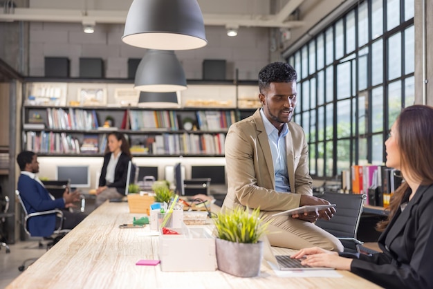 Colleagues in a boardroom discussion, seated at a table together, swapping ideas and strategizing project strategy. In the office, young business professionals