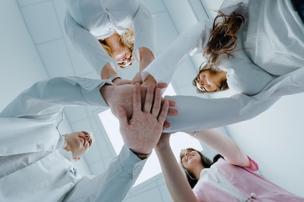 Colleagues of doctors of different genders put their hands on each other together A team of professionals at the hospital Bottom view