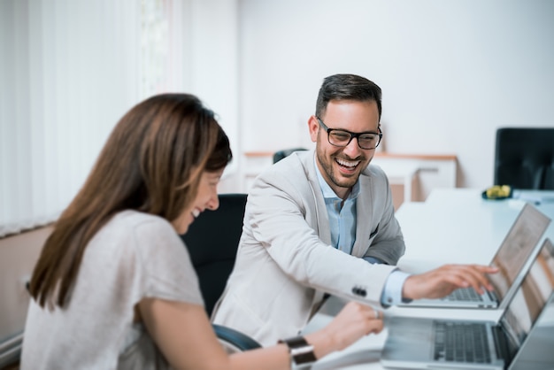 Colleagues laughing together in office during work