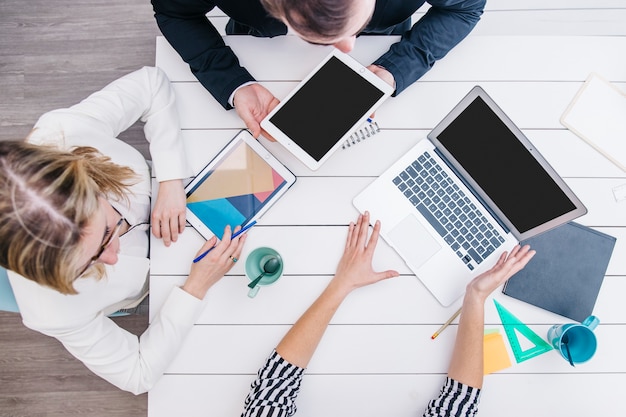 Colleagues using gadgets at desk