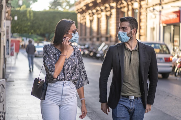 Colleagues walking in the city center wearing protective mask to prevent the spread of the coronavirus Young people talking together outdoors