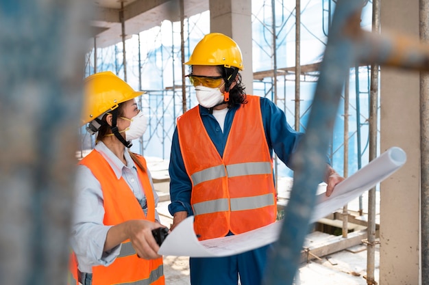 Colleagues with safety equipment working with blueprints