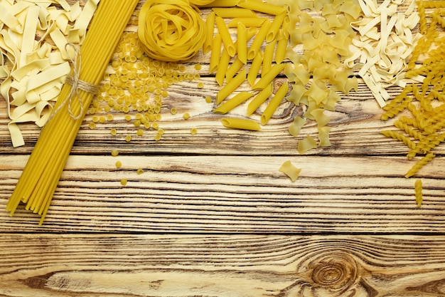 Collection of italian pasta top view on vintage wooden background.