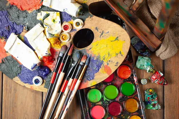 A collection of paint brushes and other items on a wooden table.