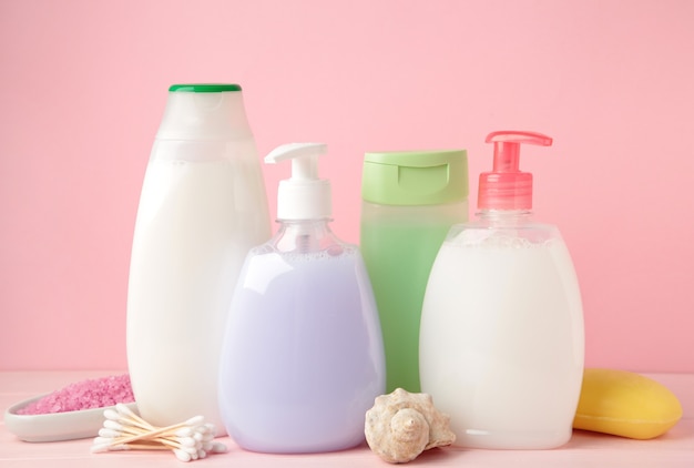 Collection of various beauty hygiene containers on pink wall. Shower gel. Top view